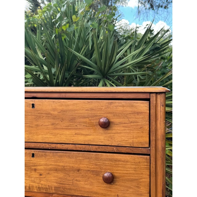 Charming antique pine chest of drawers featuring four spacious drawers, original round wooden knobs, and a beautifully...