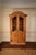 A handsome matched pair of large-scale Provincial style pine display cabinets featuring graceful arched crowns, paneled...