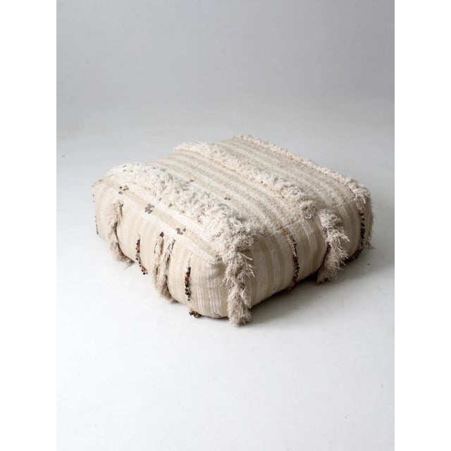 This is a vintage Moroccan style floor pillow. The large floor pouf has a cream and beige striped covering with fringe and...