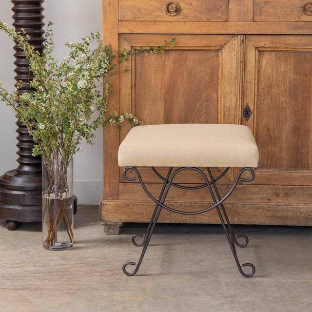Iron stool with beautiful curved and looped base with matte black painted finish. Rectangular cushioned seat upholstered...