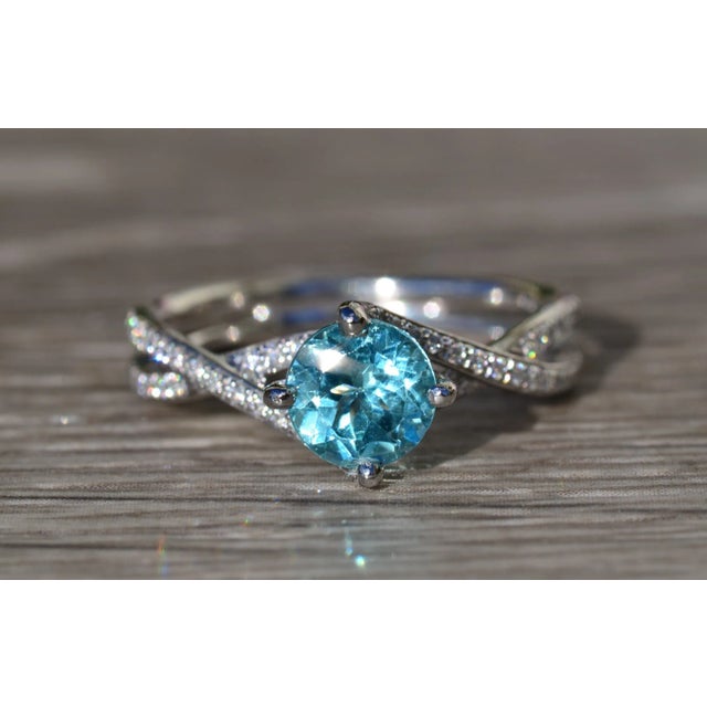 The El Cajon Pariaba Engagement Ring in Platinum. The ring centers on a 1.10 carat vivid very slightly greenish-Blue...