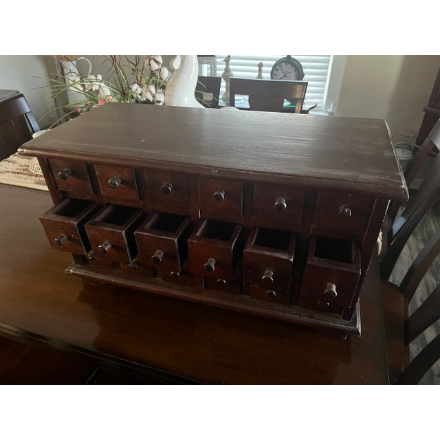 Apothecary Cabinet all Wood and has Eighteen Fully Functioning Drawers . Cabinet is in a Medium to Dark Color Wood .