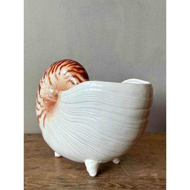 This charming vintage ceramic cachepot is meticulously molded and glazed in the shape of a nautilus shell, embodying the...