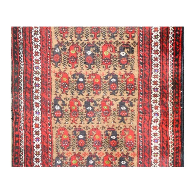 A wonderful vintage Afghani Baluch prayer rug with an all-over paisley pattern woven in crimson and brown wool set against...