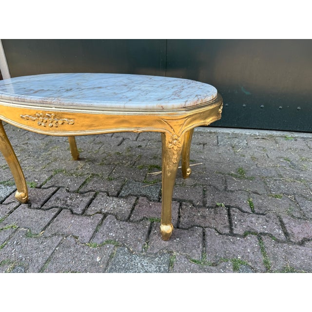 A refined 1940 French Louis XVI-style coffee table, crafted from gilded beech wood and finished with its original marble...
