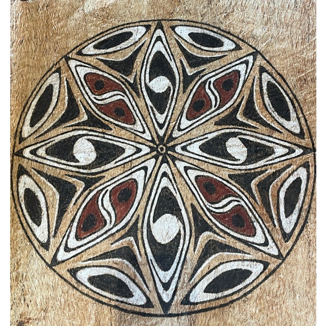 This piece features a striking symmetrical design, with circular, spiral, and diamond motifs carefully hand-drawn in black...
