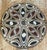 This piece features a striking symmetrical design, with circular, spiral, and diamond motifs carefully hand-drawn in black...