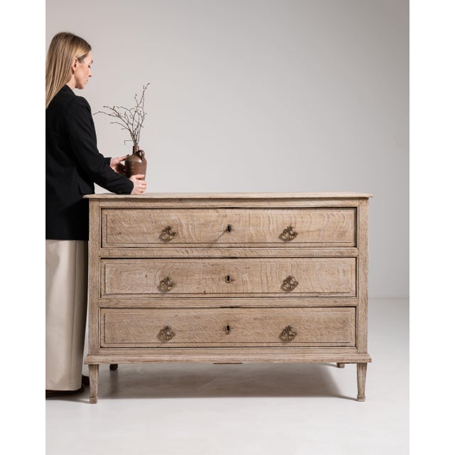 A substantial oak chest of drawers showcasing traditional French craftsmanship and functional design. The solid...