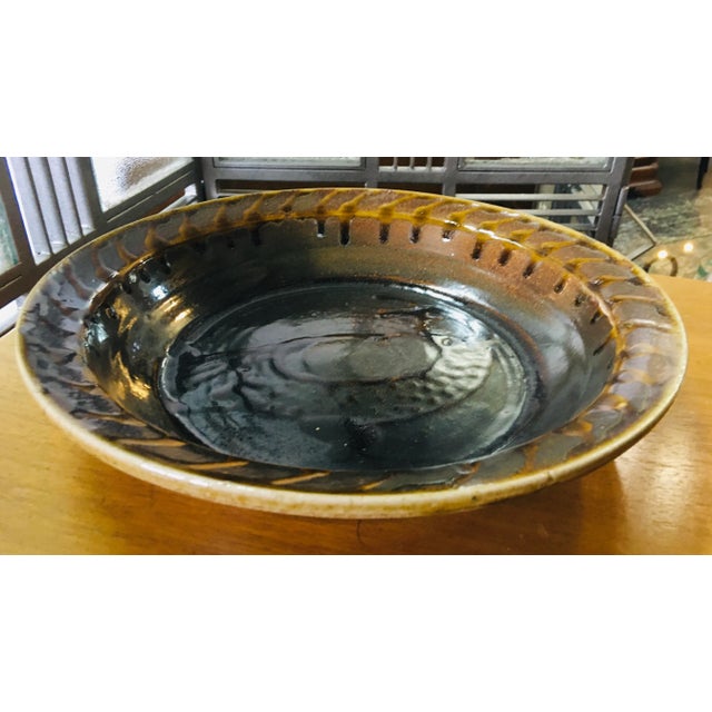 This is a mid century artisan studio pottery bowl. This bowl features a dark rich brown glaze with a bird painted to the...