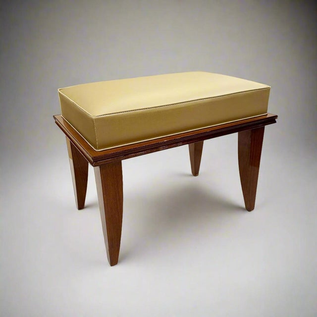 A modernist bench in the style of Leleu. A boxed rectangular seat supported by a framed base and tapering legs in mahogany...