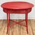 Vintage wicker table with oval slatted wood top in a weathered bold red paint. Four wrapped legs attached by x-base...