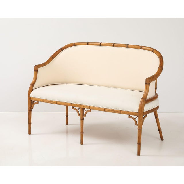 This elegant Hollywood Regency faux bamboo settee features a graceful curved back with an exposed faux bamboo frame. The...