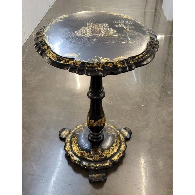 Circa 1840, papier mache black lacquered and inlaid mother-of-pearl tilt top table featuring a religious scene. The scene...