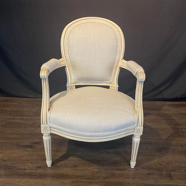 Elegant pair of 19th century French Louis XVI fauteuils with carved painted frames featuring fluted, tapered legs, stop-...