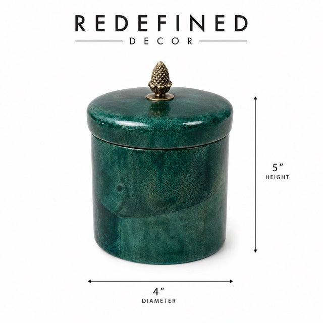 A striking cylinder box wrapped in deep emerald lacquered goatskin, finished with a fitted brass lid crowned by a...