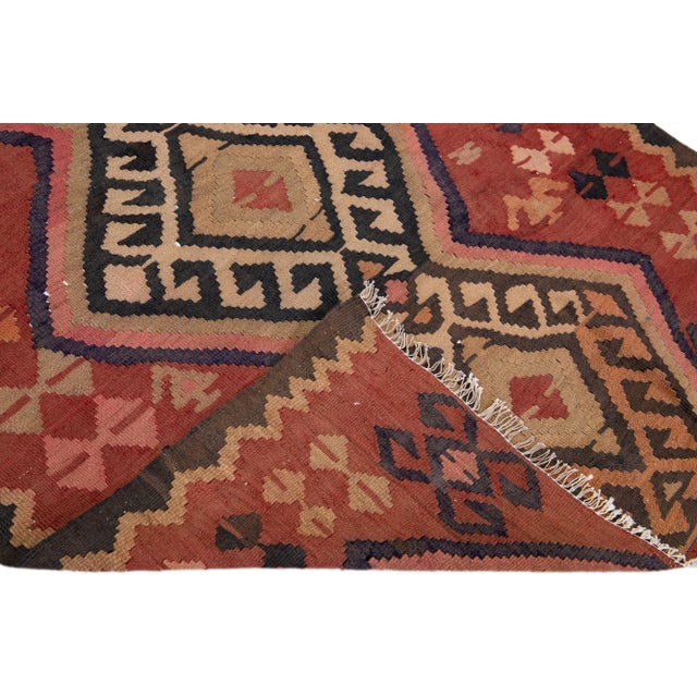 Beautiful vintage Turkish Kilim hand-knotted wool rug with a red field. This piece has a tan frame and multicolor accents...