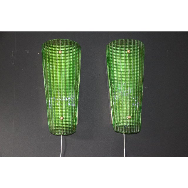 This stunning pair of wall sconces features a deep, vibrant emerald color. Crafted entirely from textured Murano glass,...
