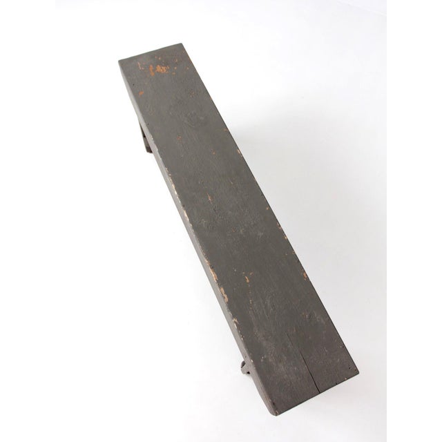 Late 19th-century primitive Americana bench with a long, narrow form, shaped plank supports, and a beautifully aged dark...