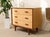 A handsome lowboy dresser featuring three wide drawers with beautifully figured birdseye maple fronts. The light, richly...