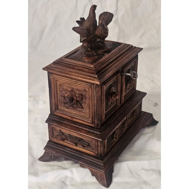 A beautifully expressive c.1880 Black Forest jewelry box, richly carved from warm walnut and crowned with a tender pair of...