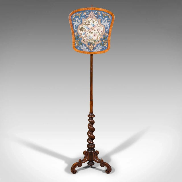 This is an antique pole screen. An English, rosewood adjustable needlepoint tapestry fire shield, dating to the Regency...