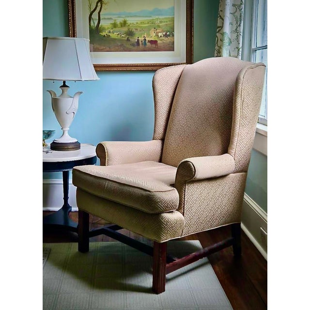 This handsomely designed wingback chair is covered in a geometric print that is subtle because of its neutral color...