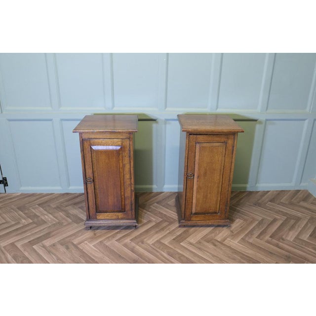 A Pair of Arts and Crafts Oak Bedside Cupboards A pair of Good Quality Golden Oak Bedside Cabinets, both cupboards have a...