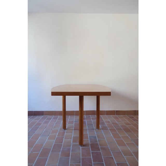 A very large dining table from the 1980s, with a lacquered top in a warm honey tone and four turned legs finished with...