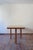 A very large dining table from the 1980s, with a lacquered top in a warm honey tone and four turned legs finished with...