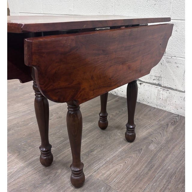 This is an antique 19th-century walnut Pembroke drop-leaf table featuring a richly figured solid wood top, shaped leaves,...