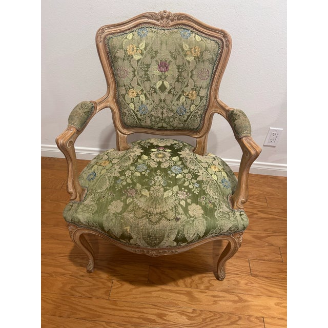 Pair of French Louis XV-style bergère armchairs featuring beautifully carved beechwood frames with a softly distressed...