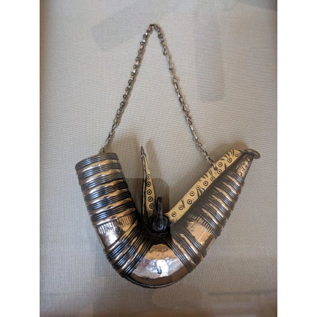 A handsome vintage, multi-metal, Middle Eastern powder horn in a 2.5-inch deep wooden shadow box frame lined with beige...