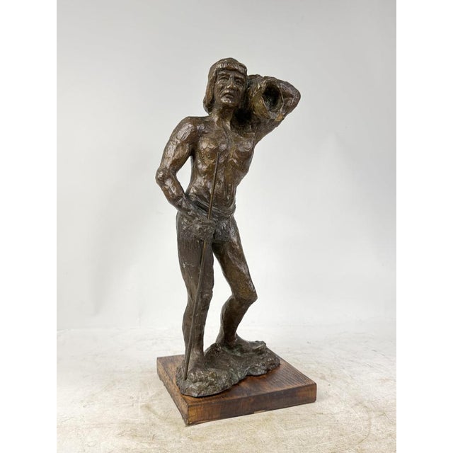A beautiful, handcrafted bronze sculpture depicting a man with a shell and a staff. The work rests on a wooden base, ideal...