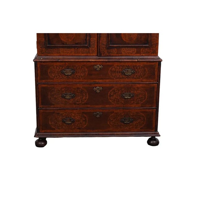 The 1800 Dutch Marquetry Dome Top Linen Press on Bun Feet is an antique double wardrobe made of walnut with a solid wood...