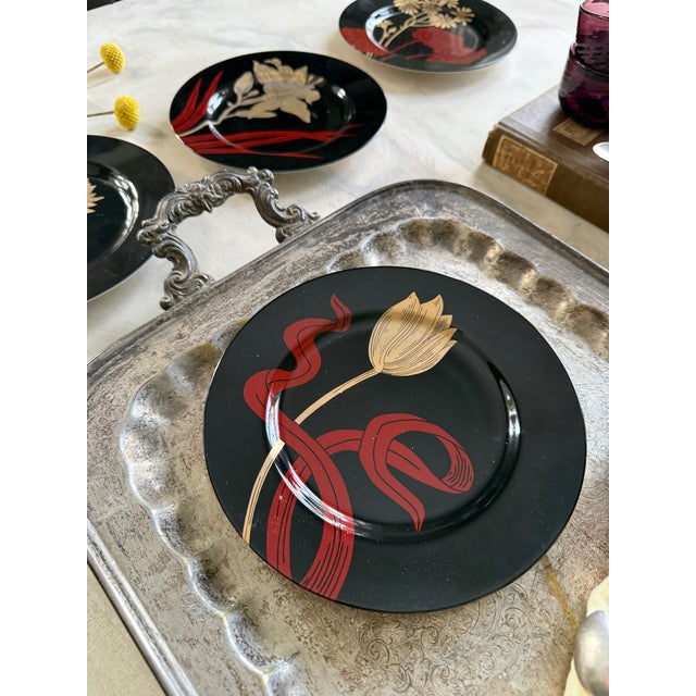 Striking vintage set of four Fitz and Floyd black floral plates, dated 1979. These plates feature bold, stylized botanical...