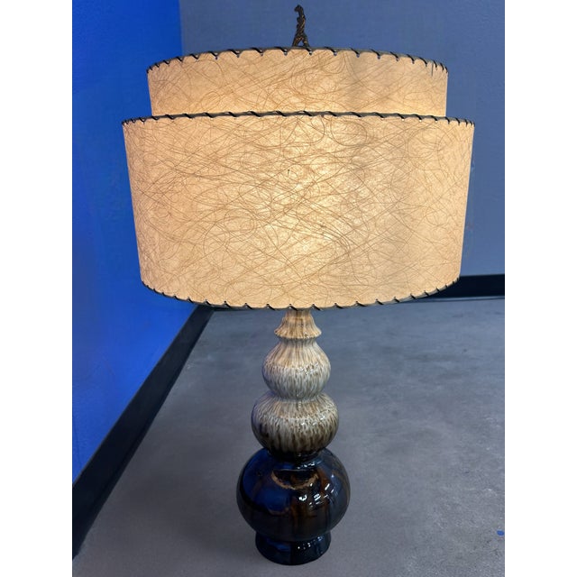 Vintage Mid Century Modern table lamp featuring a stunning double-tiered fiberglass shade with dark lacing and swirling...