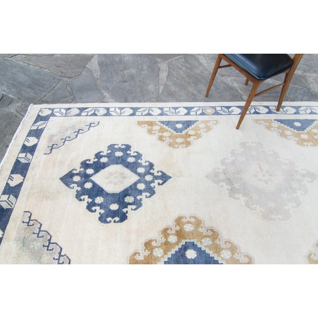 Softly neutral hues such as beige for the base, with accents in denim, moss/brown alongside a trio of medallions...