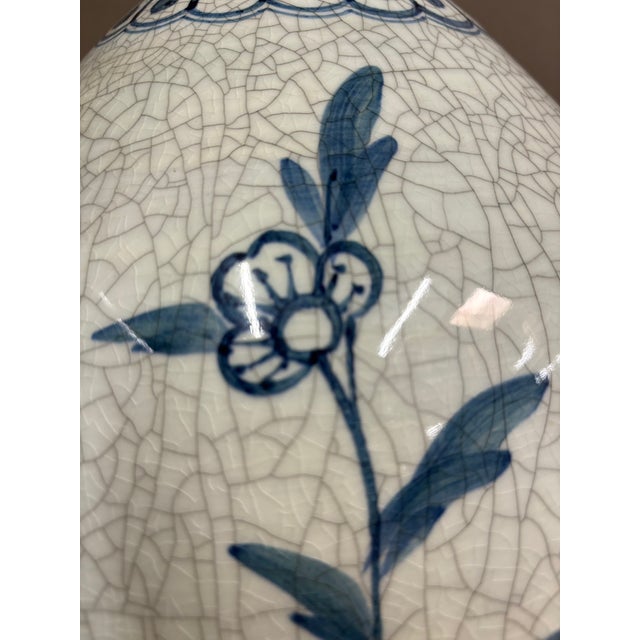 Light blue crackle vase lamp with hand painted blue flowers and leaves with pattern around the top. Dark woodenly and...