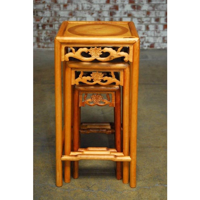 Large set of three carved Chinese nesting tables or stacking tables featuring a lotus blossom decoration on the apron and...