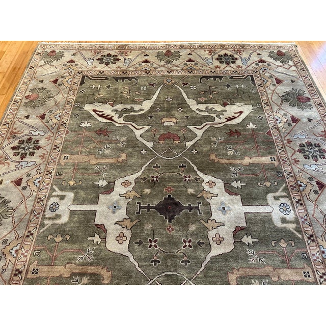 This hand-knotted wool rug features a Ziegler Persian design with a muted green field and a soft beige botanical border....