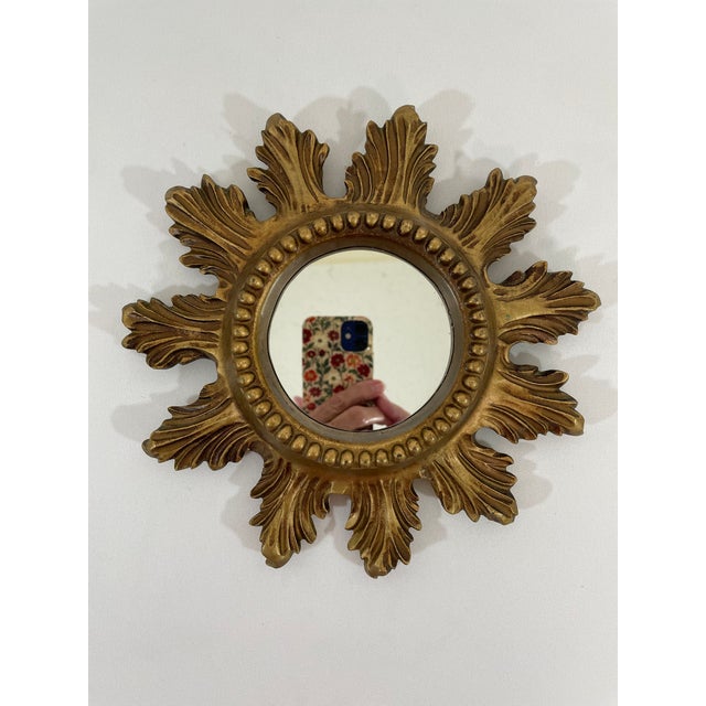 A stunning petite 8.5" Italian gilded Sunburst Accent Wall Mirror from circa the 1960s. This lovely smaller sized mirror...