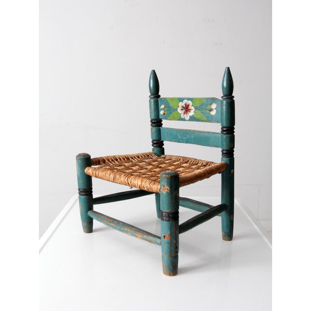 This vintage Mexican folk art child’s chair from Mexico features a hand-painted floral crest rail set against a soft...