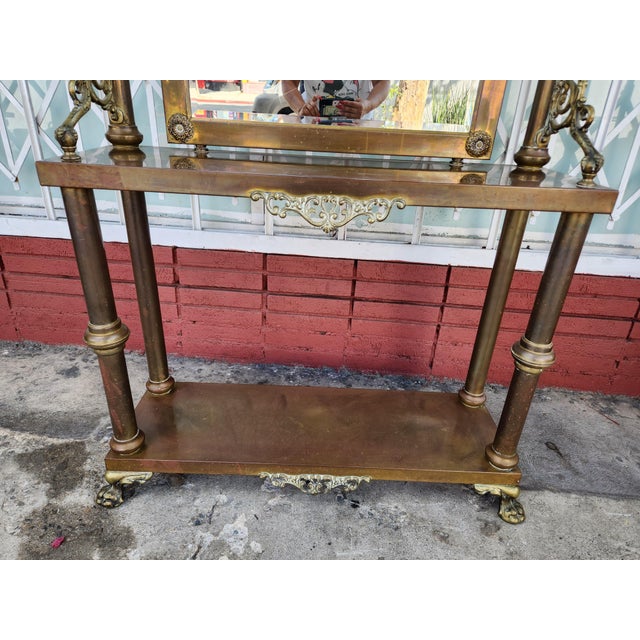 Ornate hall tree is constructed from brass- with a large rectangular central mirror. This piece has four double-pronged...