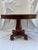 A single round antique pedestal center table featuring a solid cherry top and turned pedestal supported by a mahogany...