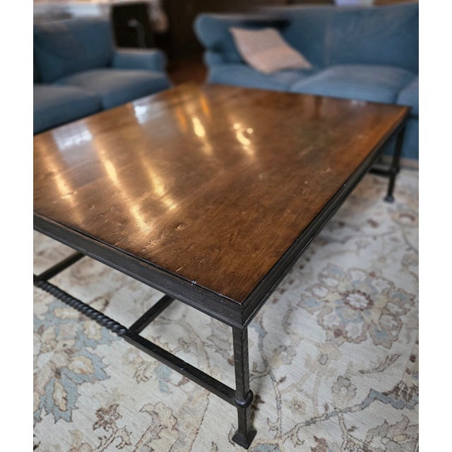 Large coffee table from Paul Ferrante in a beautiful walnut with an iron base. Measures 52x60 x 20h
