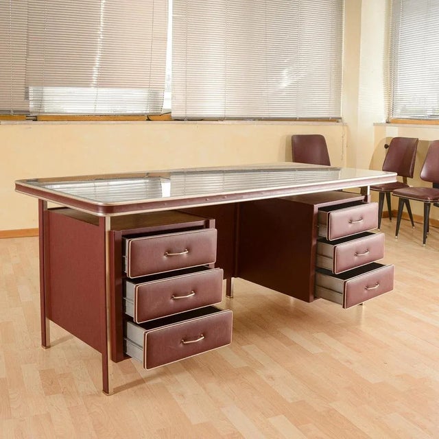 50s desk Umberto Mascagni. Of prayable construction with metal structure covered in bordeaux -like with golden metal...