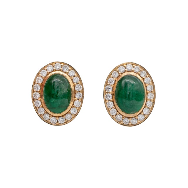 These elegant stud earrings showcase a pair of oval emerald gemstones encircled by a halo of sparkling natural earth mined...