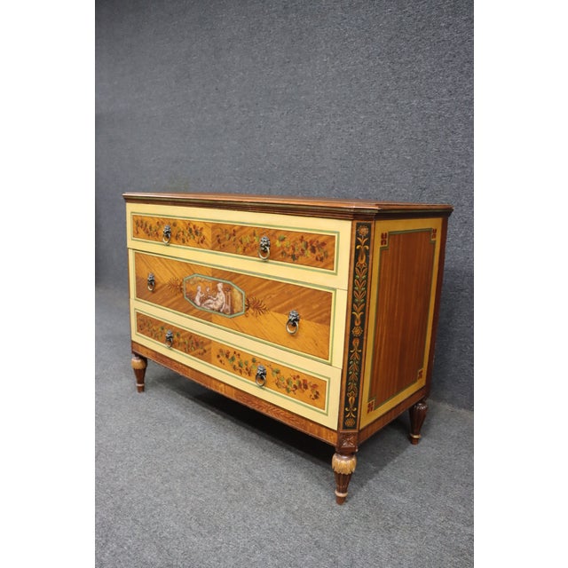 An elegant three-drawer dresser by Robert Irwin, crafted in satinwood veneers with finely painted neoclassical decoration...