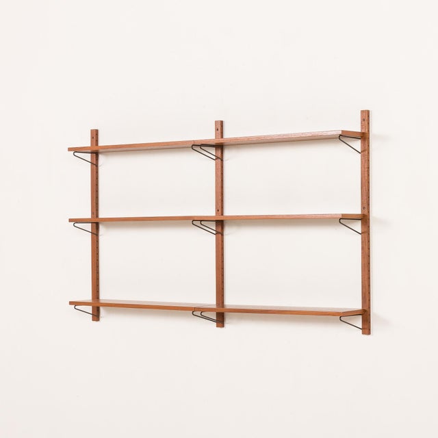 The minimalist Scandinavian mid-century shelving unit is a modular system with shelves arranged in two rows, creating an...