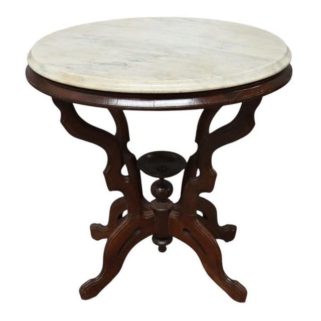 An antique Eastlake style carved walnut table, dating to approximately 1890. This elegant table features an oval white...